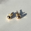 Pair of 14kt solid gold pebble stud earrings with butterfly backs on white fabric background