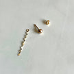 A pair of 14kt solid gold stud earrings shown disassembled on a light gray surface, with one earring showing the ball-shaped stud and the other showing the butterfly backing.