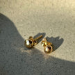 Close-up of recycled 14kt solid gold pebble studs showing polished organic texture